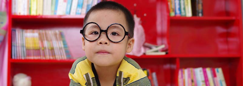 young boy wearing glasses reading in sunday school classroom at church after check-in to children's ministry.